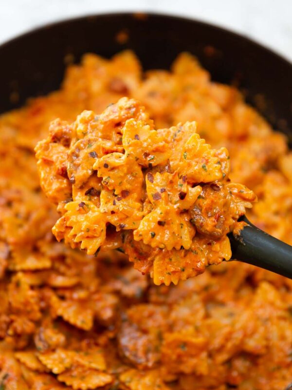 black serving spoon holding portion of spicy chorizo pasta
