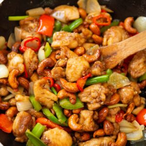 Thai chicken with cashews in wok with wooden spoon digging in