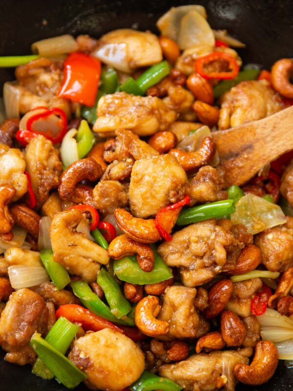 Thai chicken with cashews in wok with wooden spoon digging in
