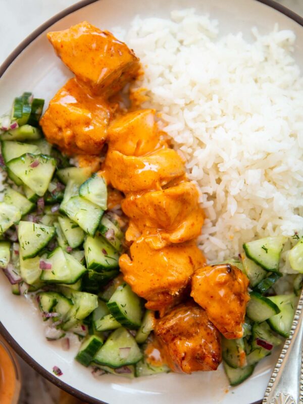 overhead shot of bang bang salmon skewers with rice and cucumber salad