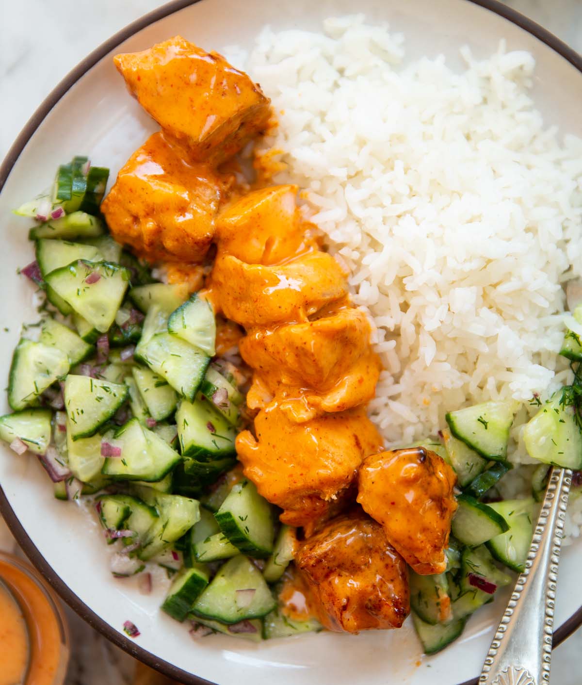 overhead shot of bang bang salmon skewers with rice and cucumber salad