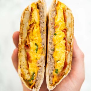 close up overhead shot of hand holding breakfast crunchwrap sliced open