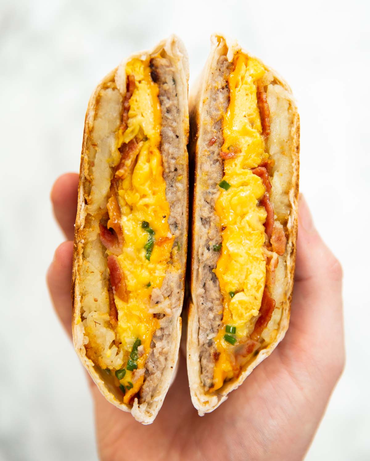 close up overhead shot of hand holding breakfast crunchwrap sliced open