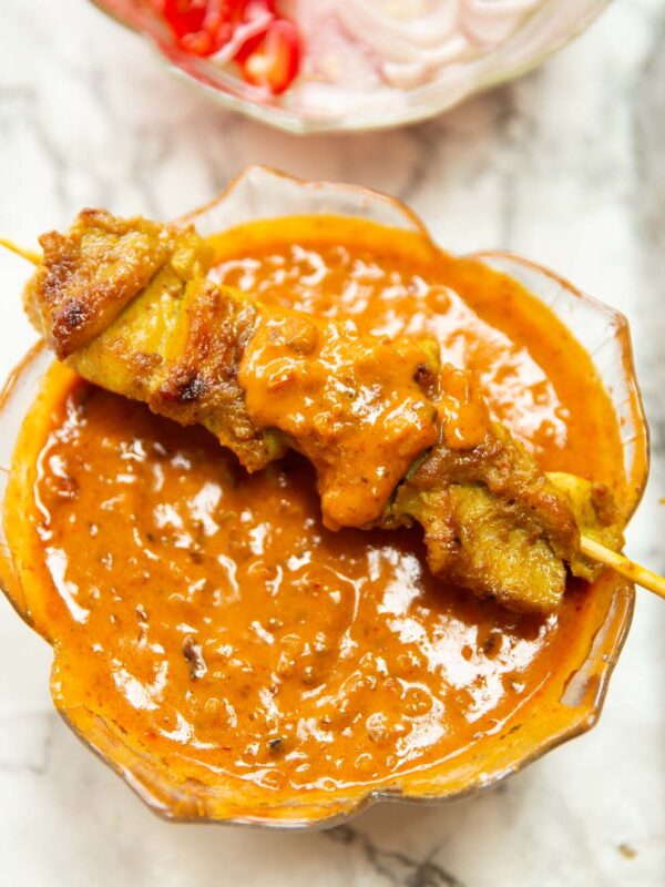 thai chicken skewer on glass pot of satay sauce