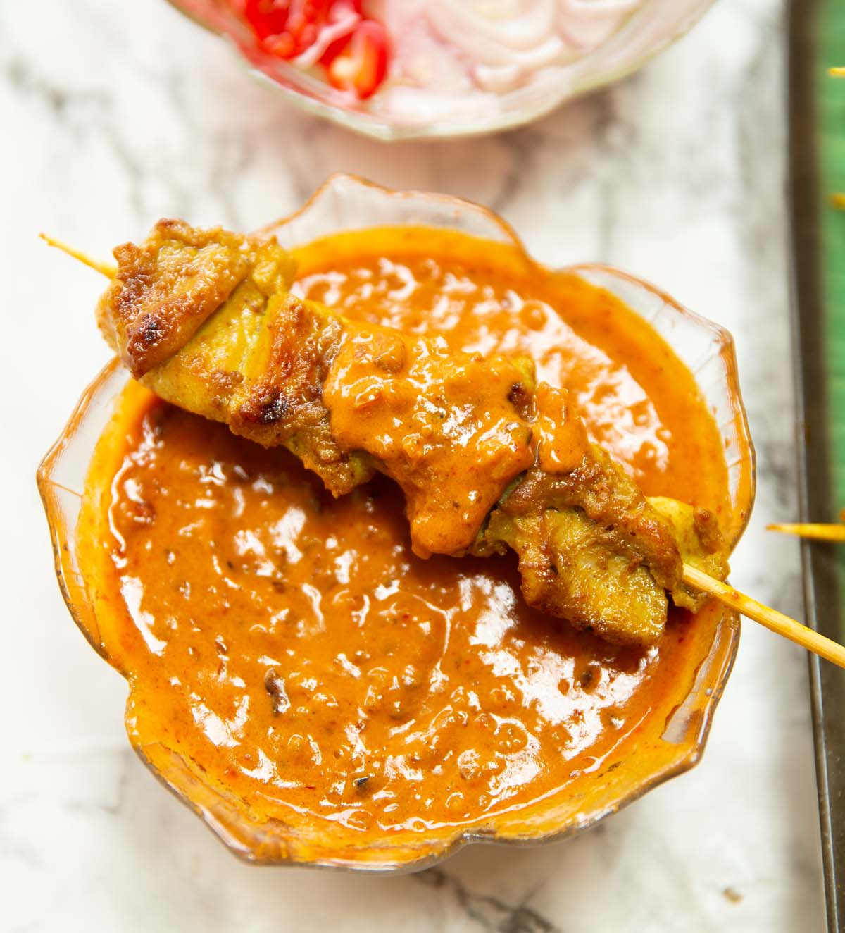 thai chicken skewer on glass pot of satay sauce