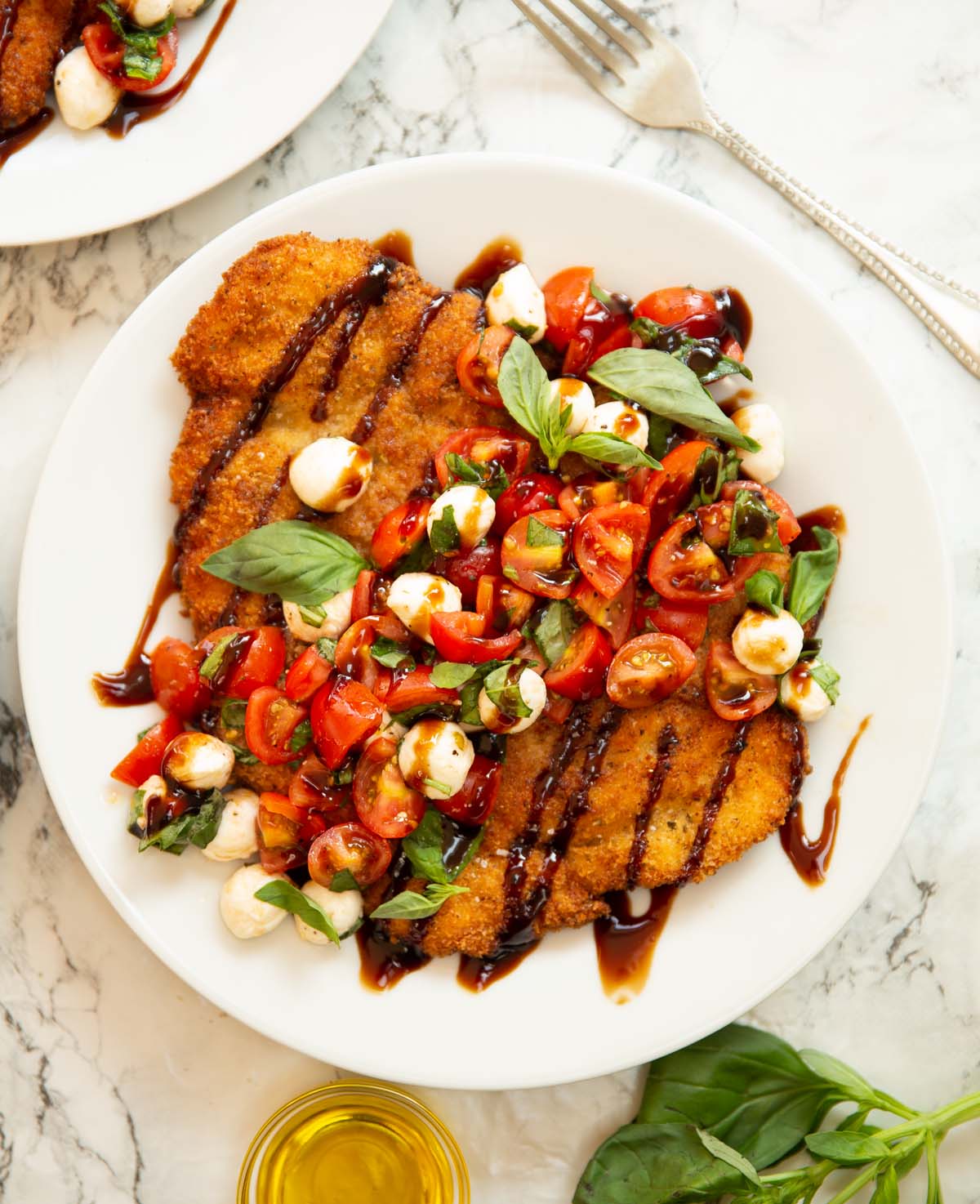 overhead shot of crispy caprese chicken on small white plate