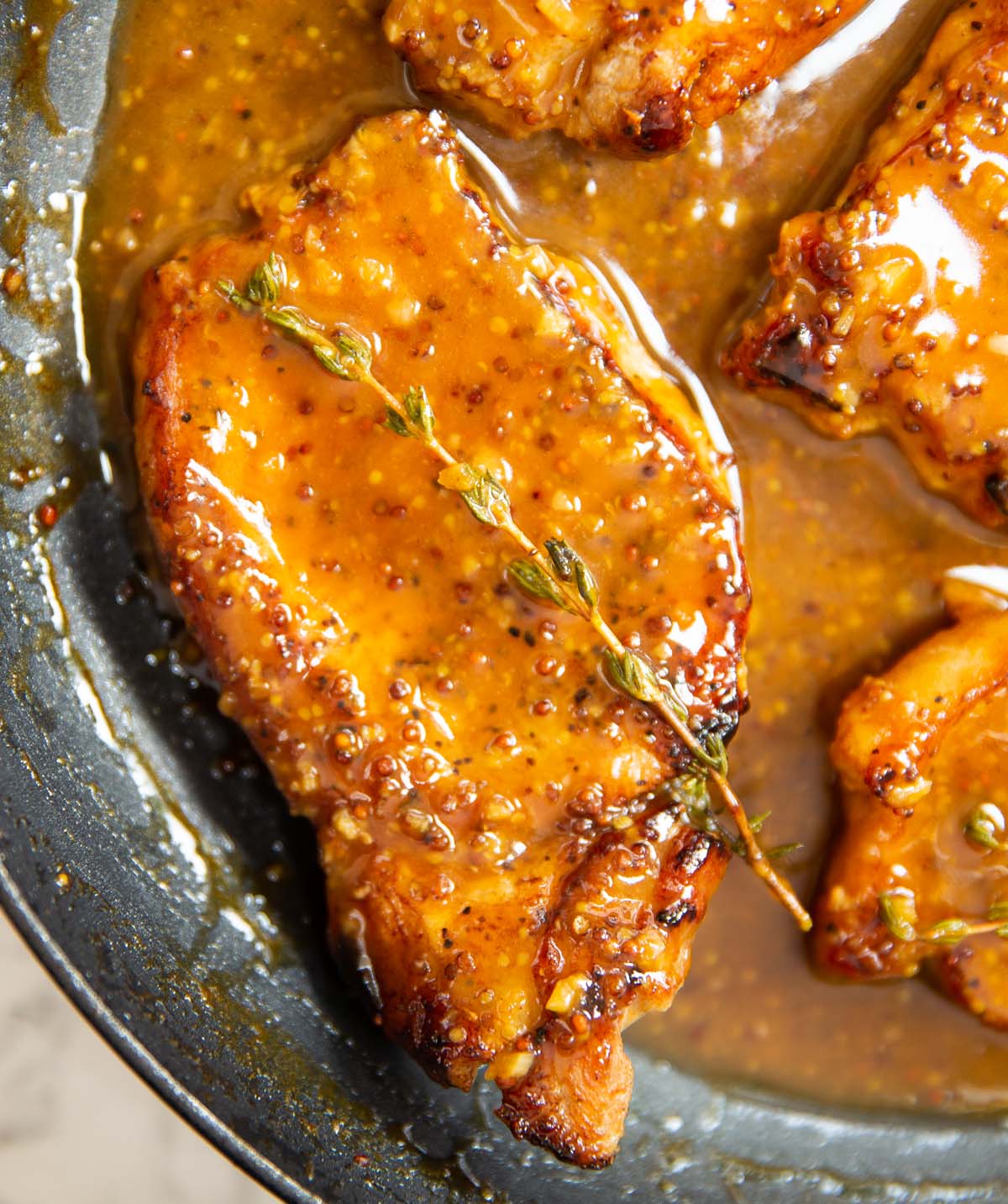 honey mustard pork chop in pan garnished with fresh thyme