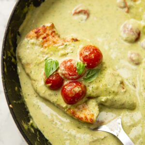pesto cream chicken in pan with spatula digging in