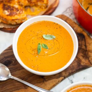 baked boursin soup in small white bowl with grilled cheese in background