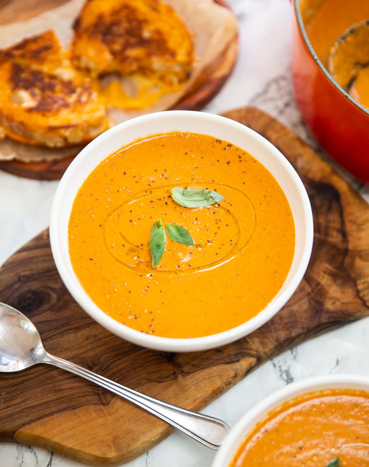 baked boursin soup in small white bowl with grilled cheese in background