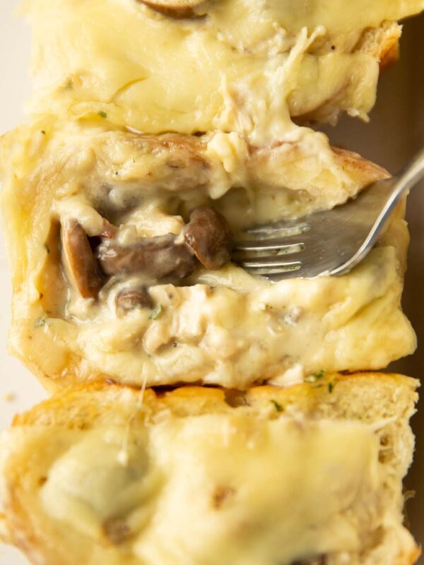 close up shot of silver fork digging into cheesy chicken mushroom slider
