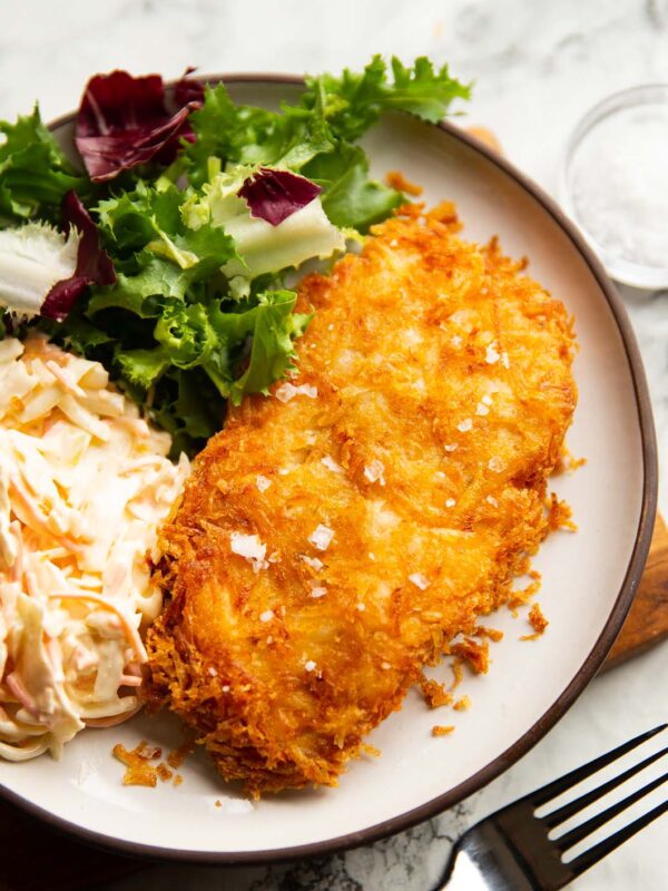 hash brown chicken served on small white plate with salad and coleslaw