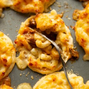 close up of silver fork digging into mac and cheese steak pie
