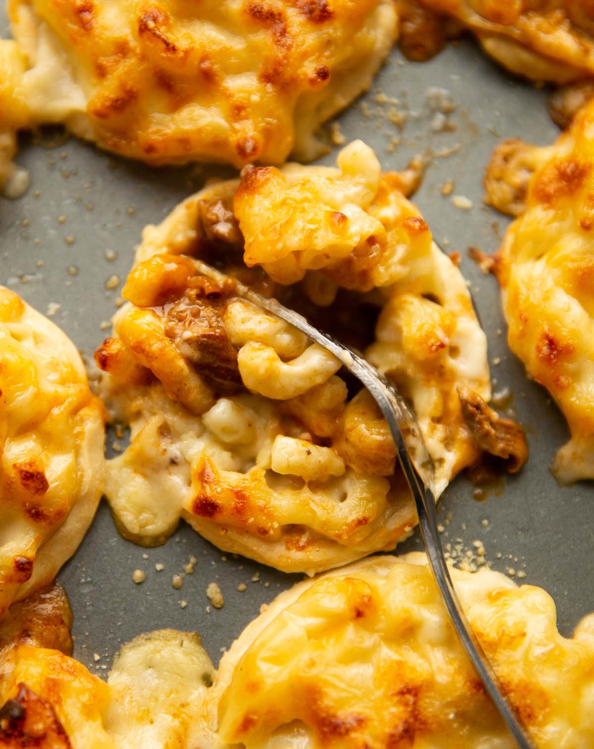 close up of silver fork digging into mac and cheese steak pie