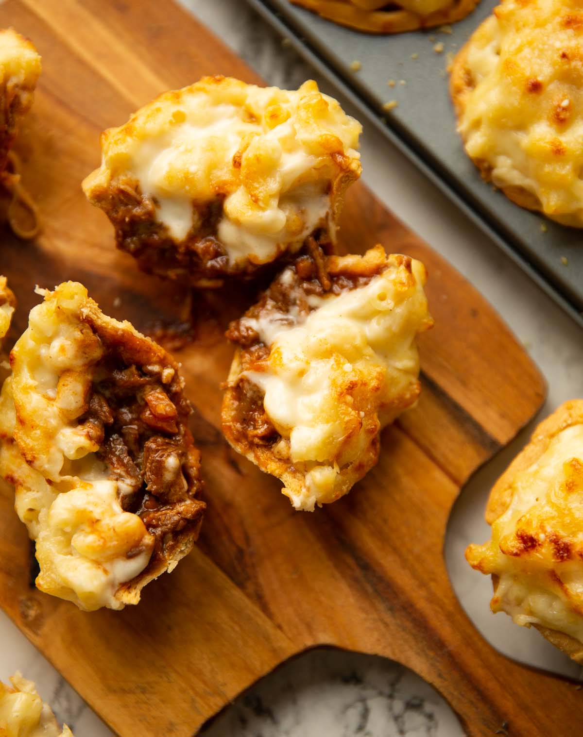overhead shot of halved steak macaroni pies on wooden chopping board