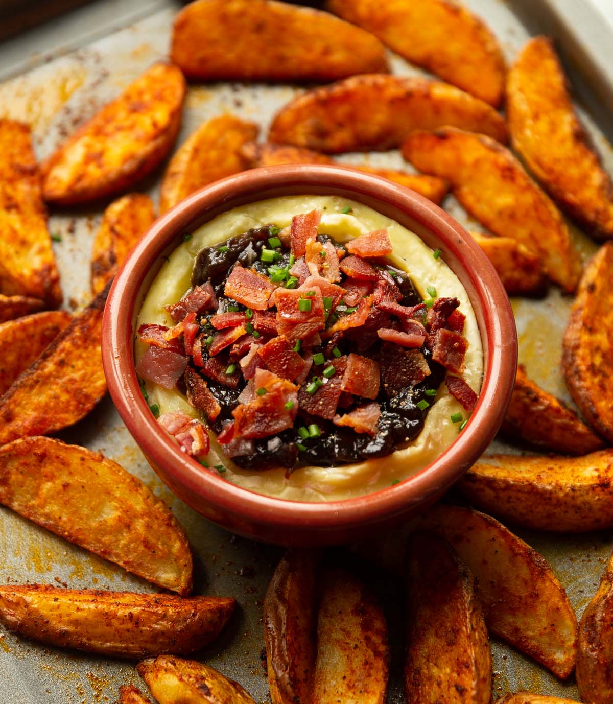 baked brie with bacon and caramelised onion on baking tray with potato wedges