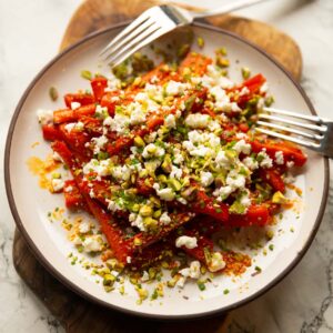 hot honey carrots on small white plate with feta, pistachios and chives