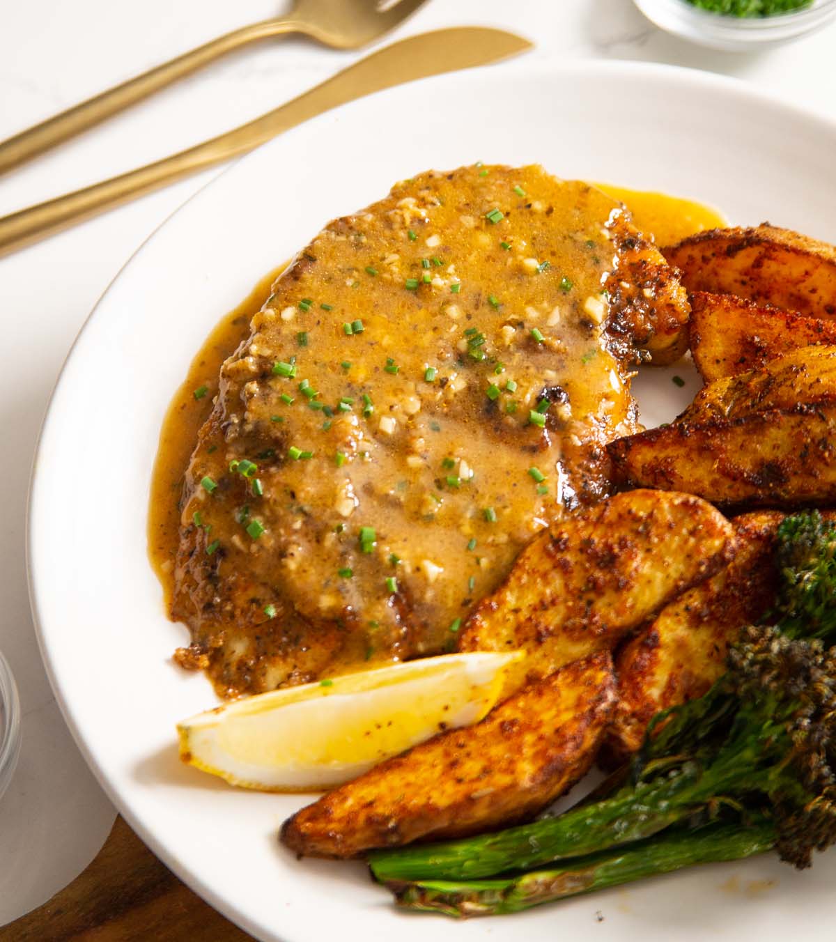 cajun chicken breast on small white plate with wedges and broccolini