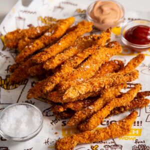 chicken fries stacked on each other with sauces in the background