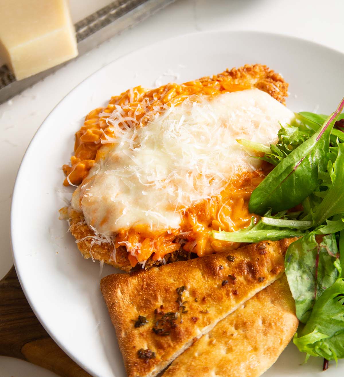 chicken on white plate with garlic bread and salad