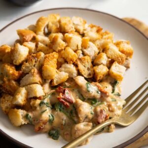 close up shot of Italian chicken bake served on small white plate with golden fork