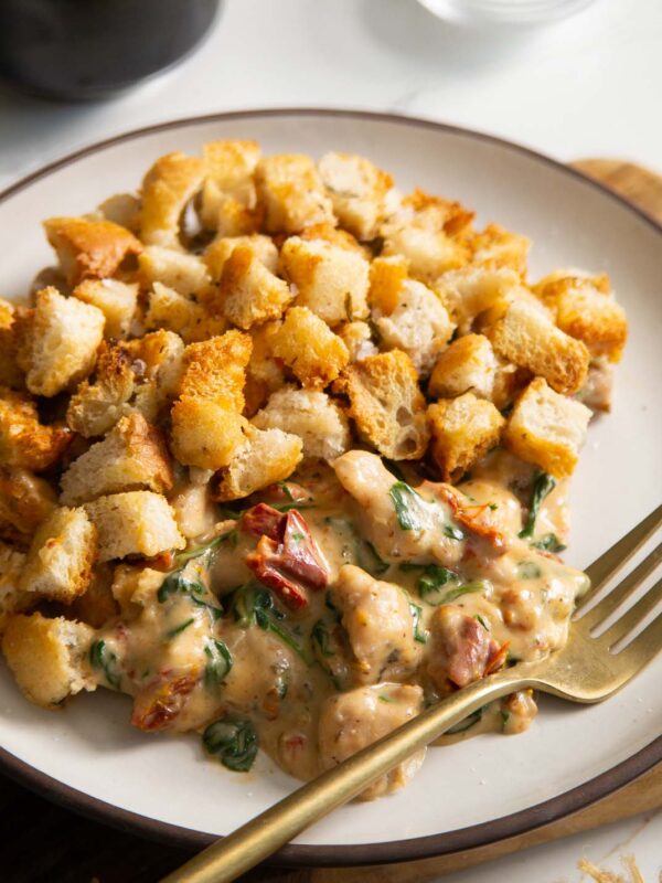 close up shot of Italian chicken bake served on small white plate with golden fork