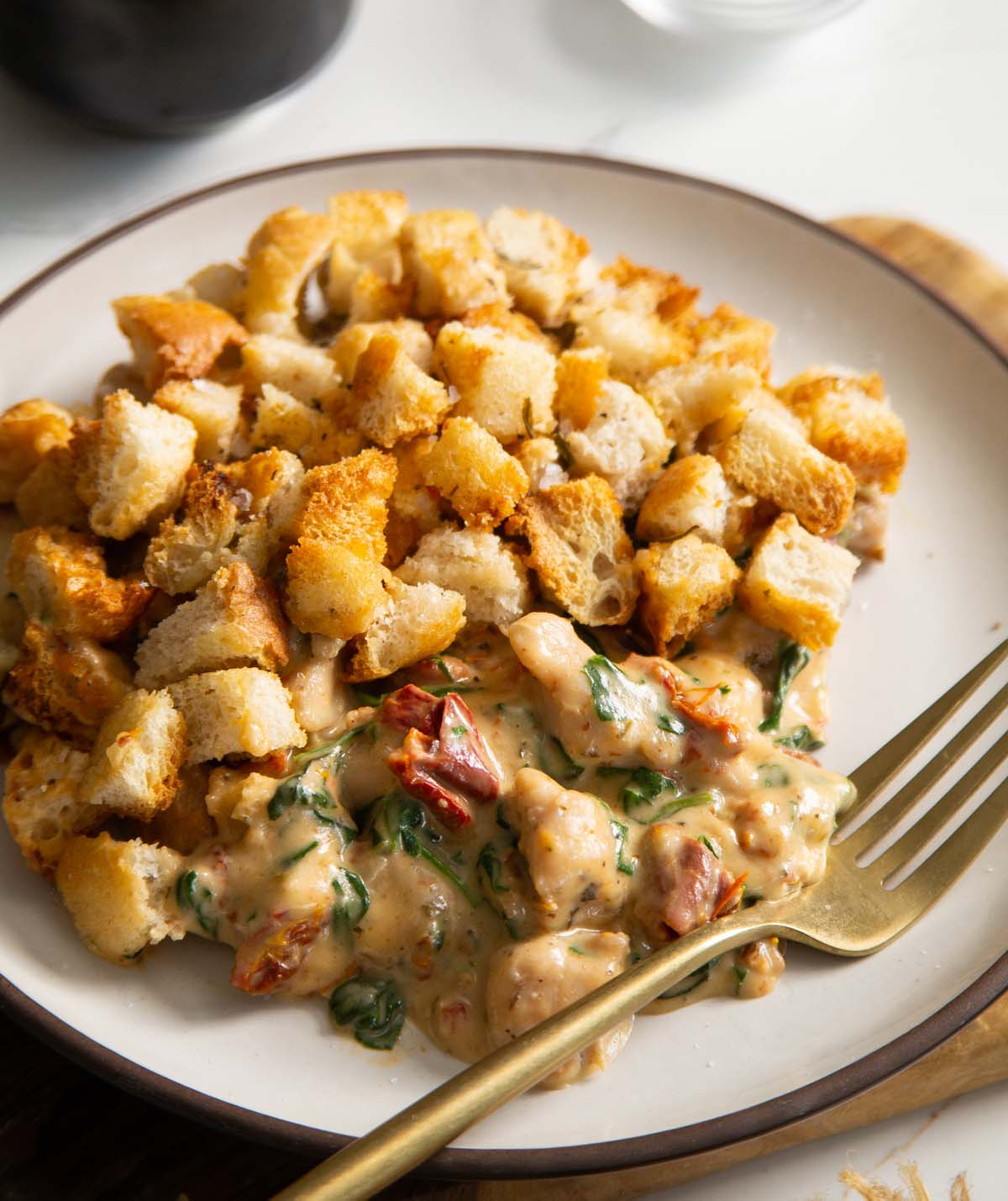 close up shot of Italian chicken bake served on small white plate with golden fork