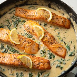 4 salmon fillets in large pan with lemon slices