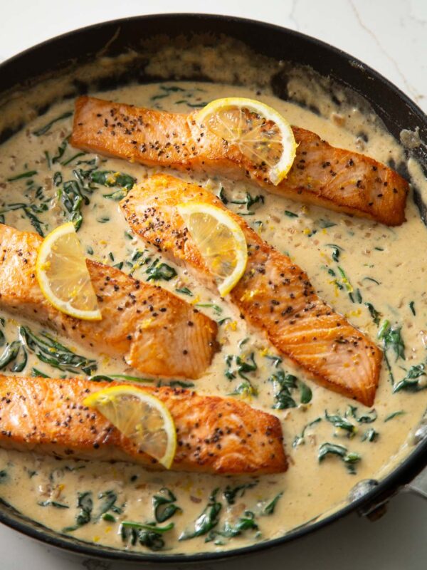4 salmon fillets in large pan with lemon slices