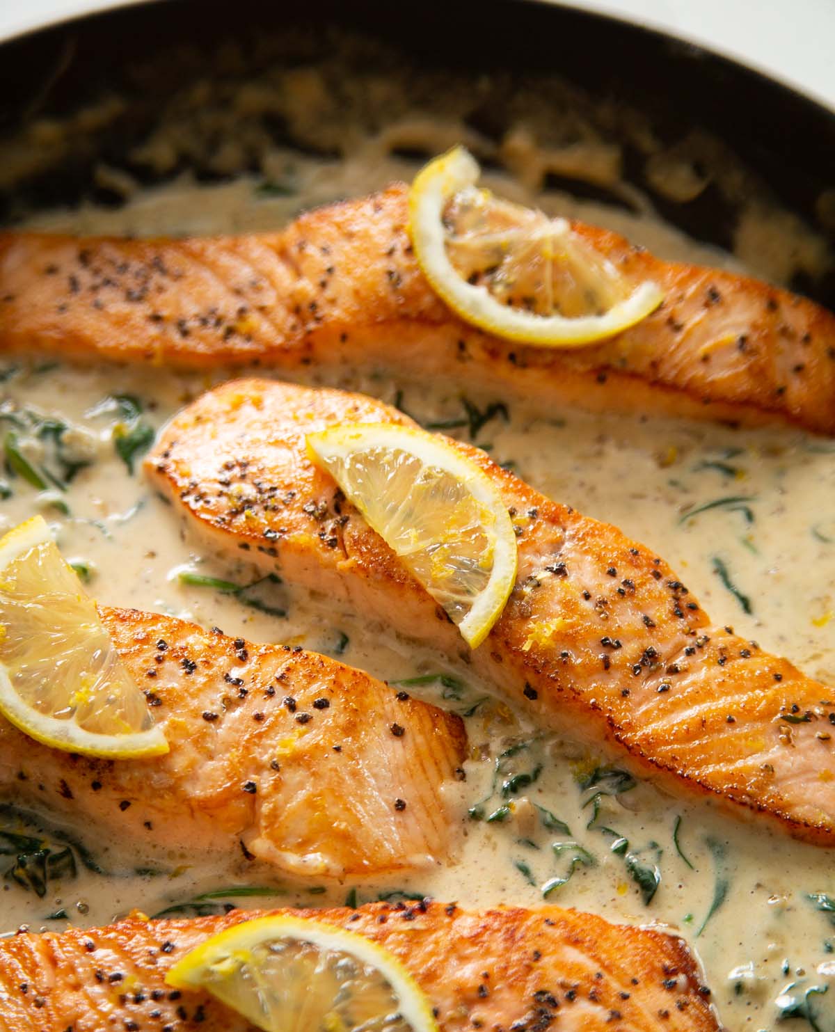 close up shot of salmon pan garnished with thin slice of lemon