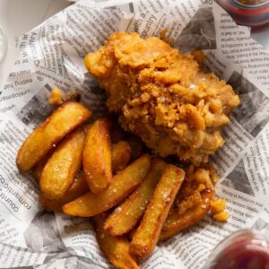 close up shot of fish and chips in newspaper with flaky sea salt