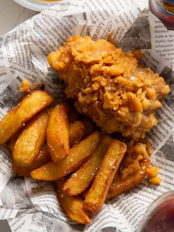 close up shot of fish and chips in newspaper with flaky sea salt