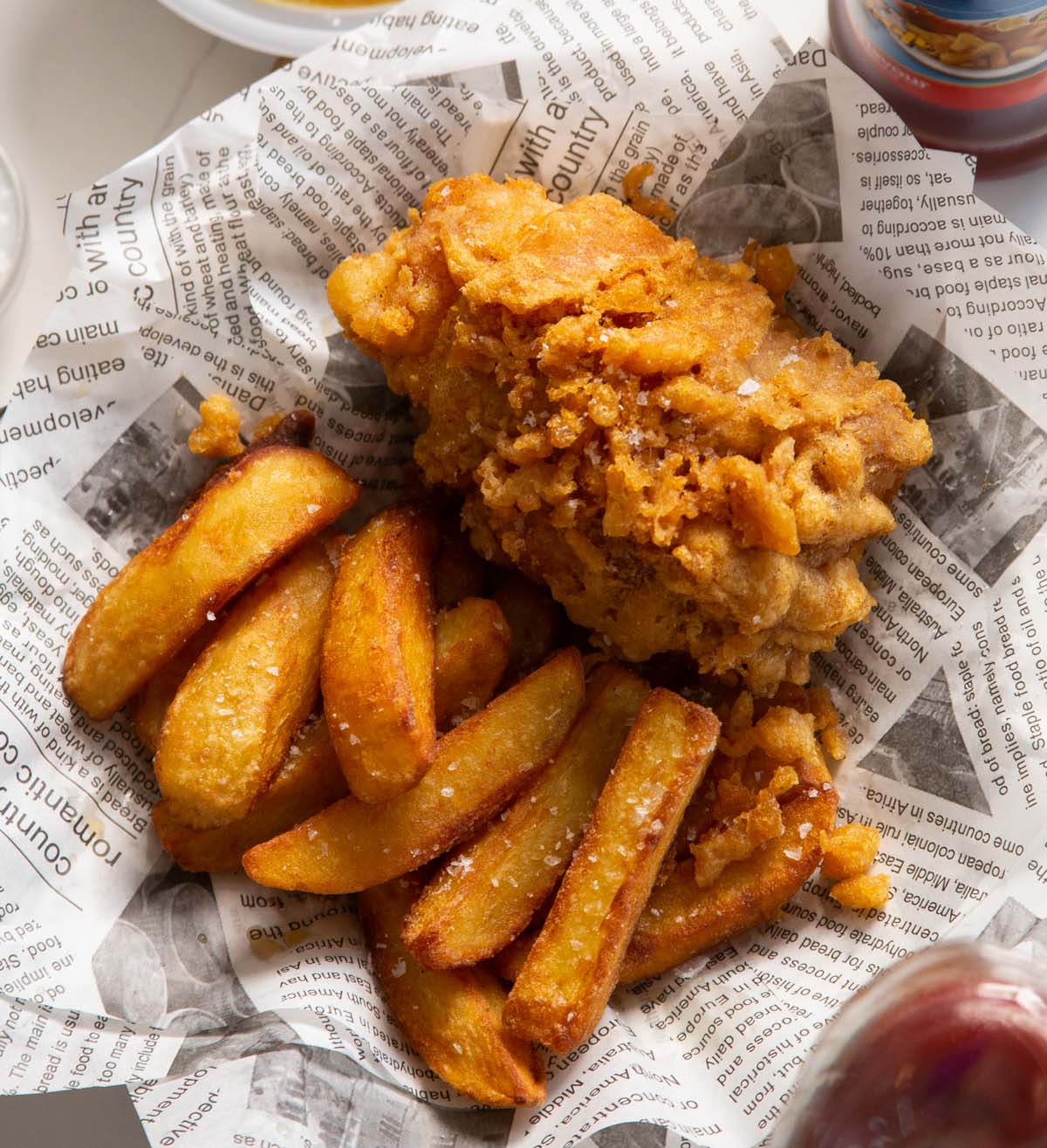 close up shot of fish and chips in newspaper with flaky sea salt