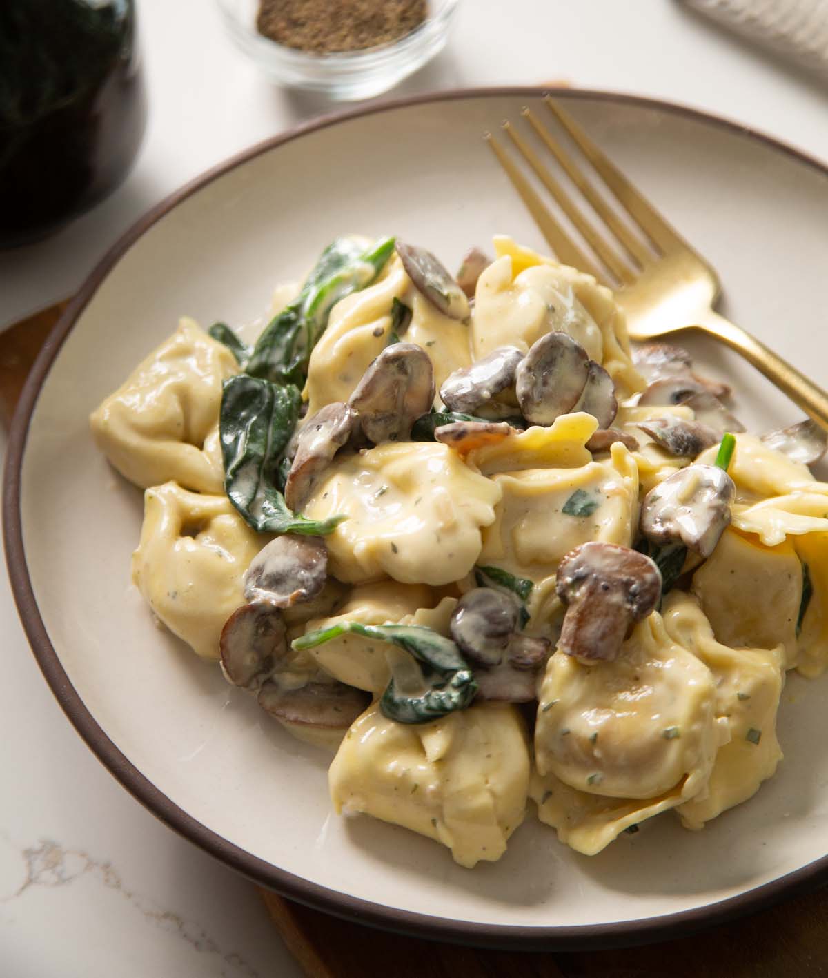 tortellini on small white place with golden fork