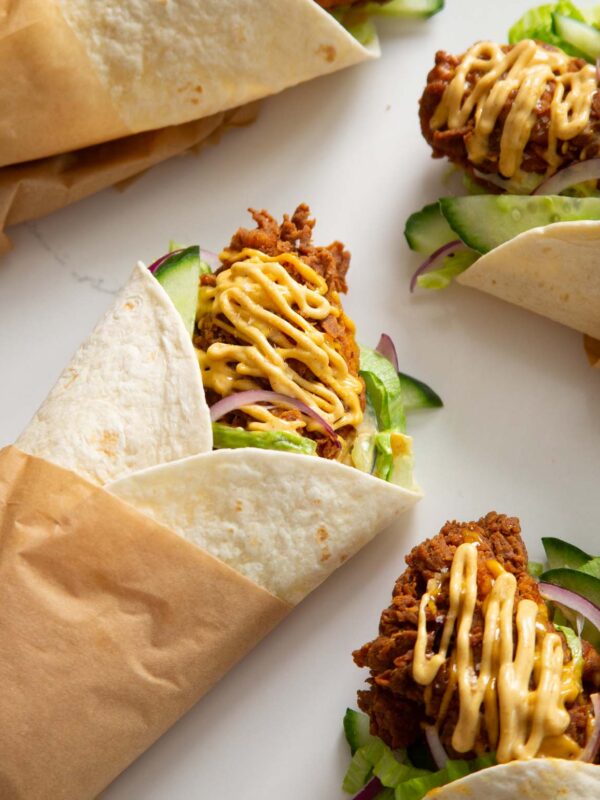 crispy chicken tikka wraps on marble island wrapped in brown baking paper