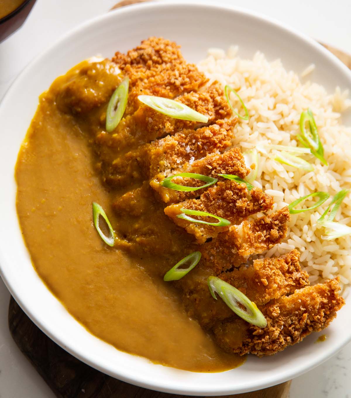 close up shot of katsu pork curry served with rice on white plate