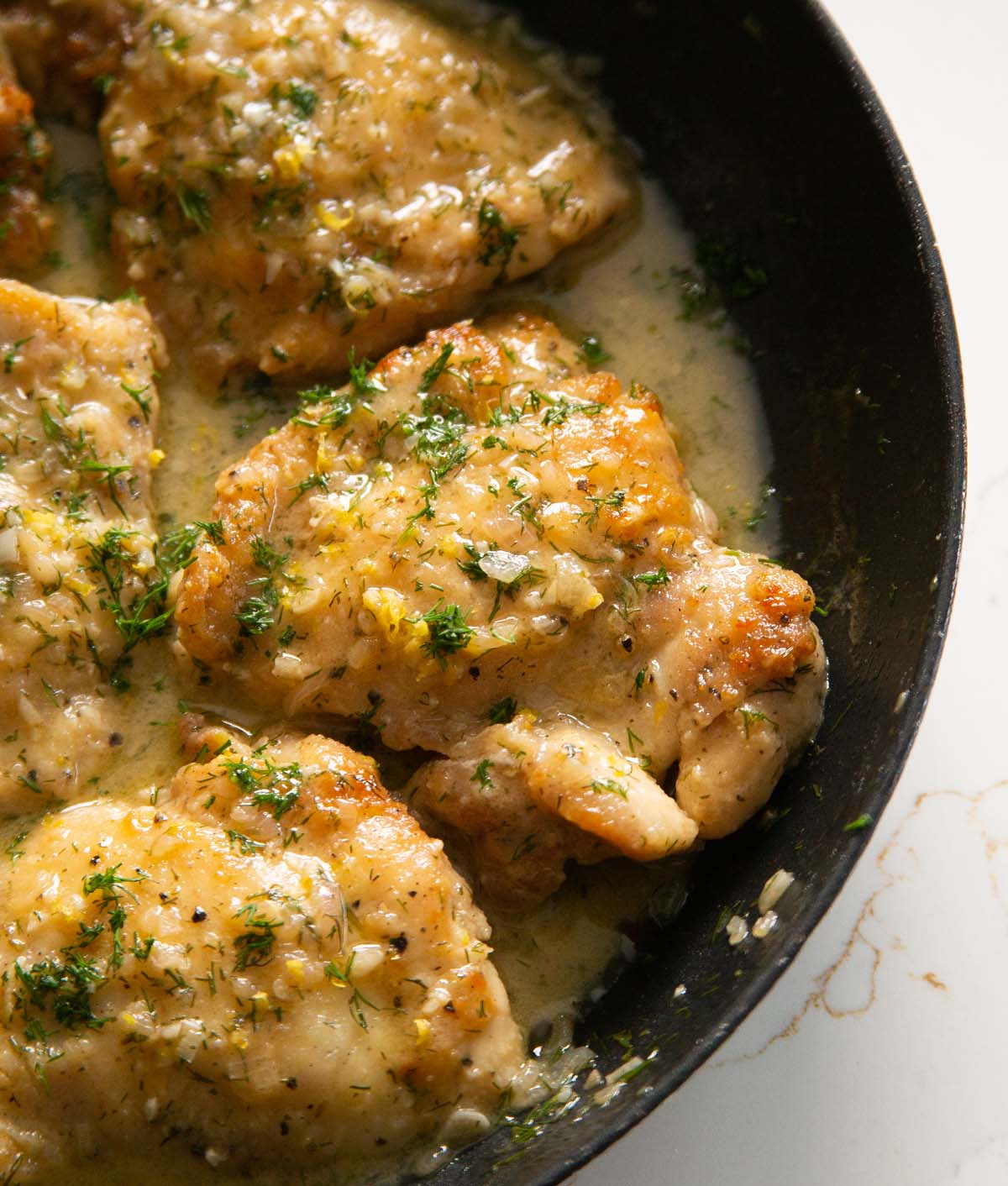 close up shot of lemon dill chicken thigh in large pan