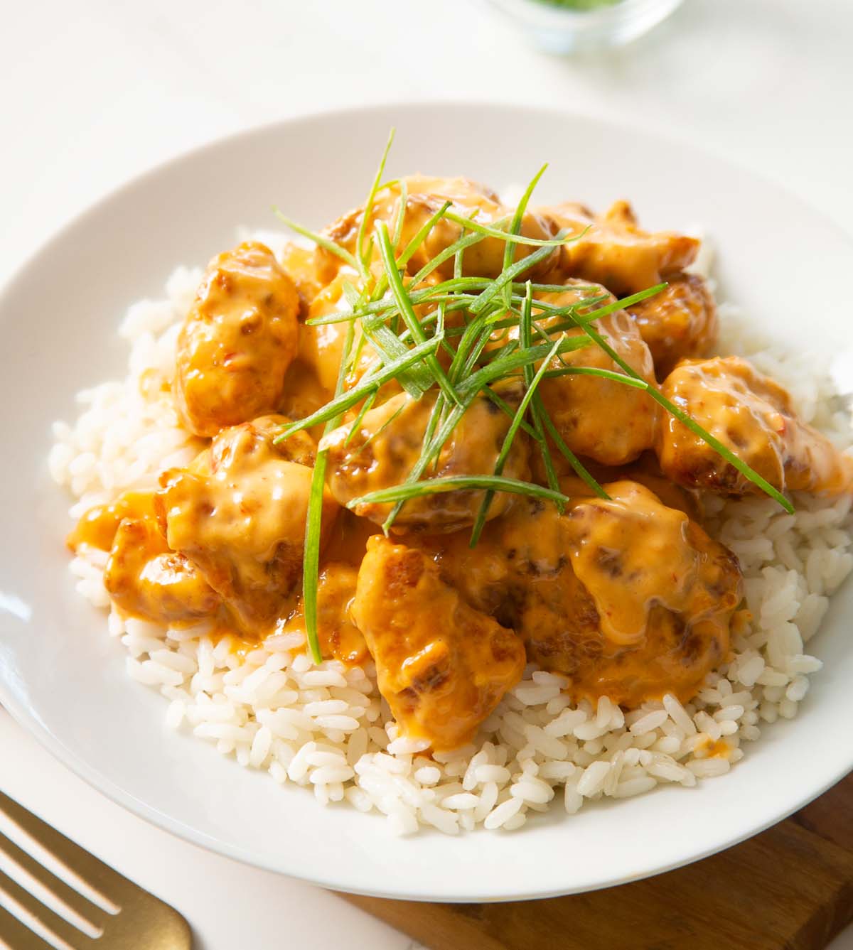 bang bang chicken on rice in white dish with thinly sliced spring onion