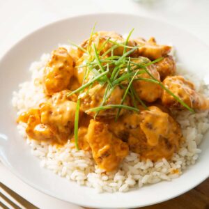 bang bang chicken on bed of rice in large white dish