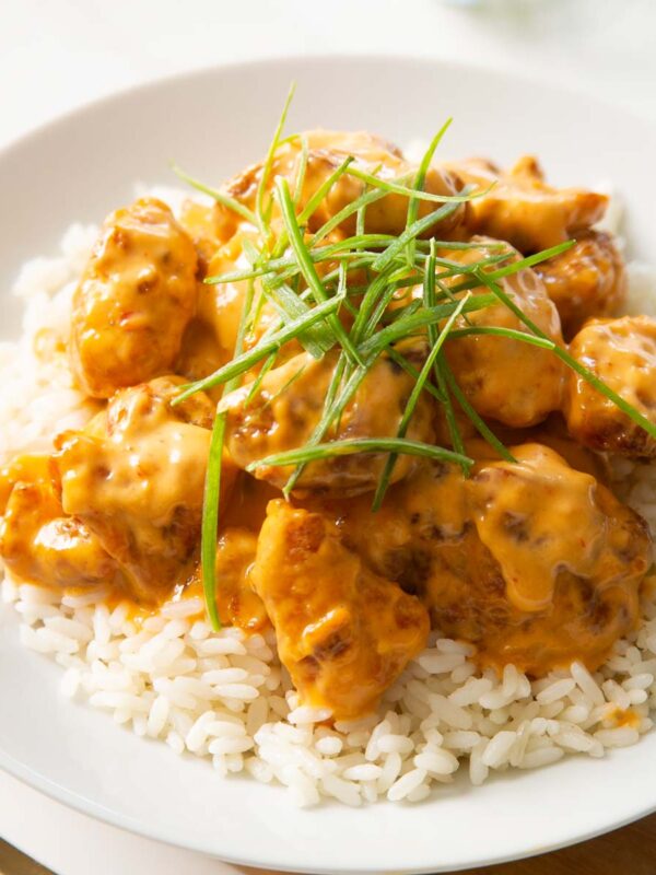 bang bang chicken on bed of rice in large white dish