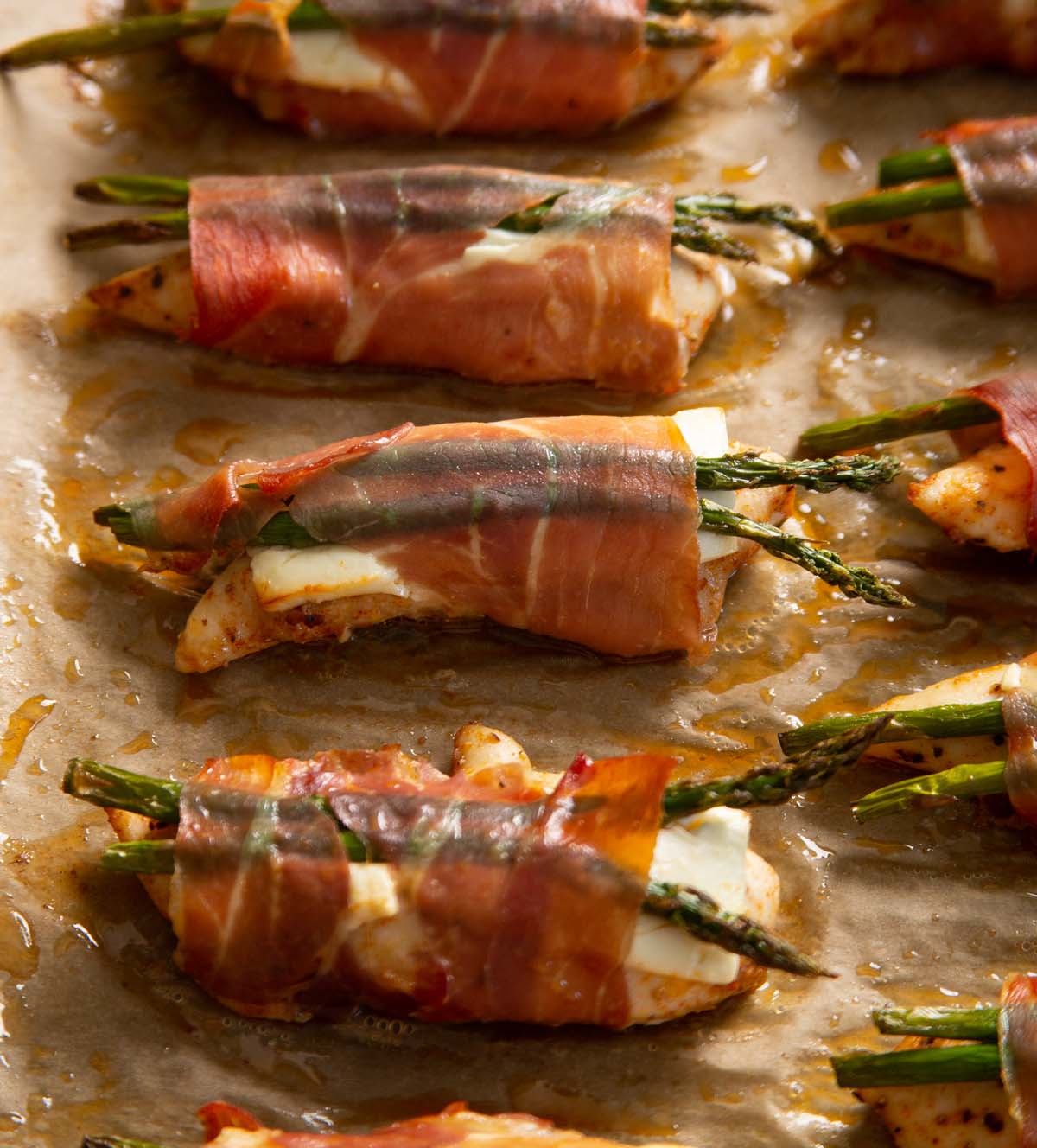 close up shot of chicken wrapped in prosciutto on large baking tray