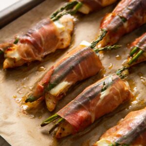 close up shot of chicken wrapped in prosciutto on baking tray fresh out the oven