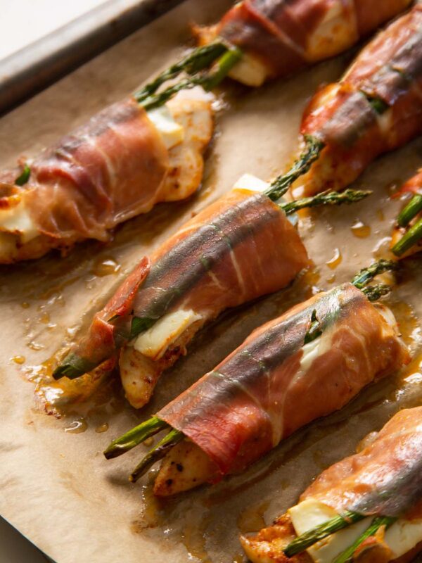 close up shot of chicken wrapped in prosciutto on baking tray fresh out the oven