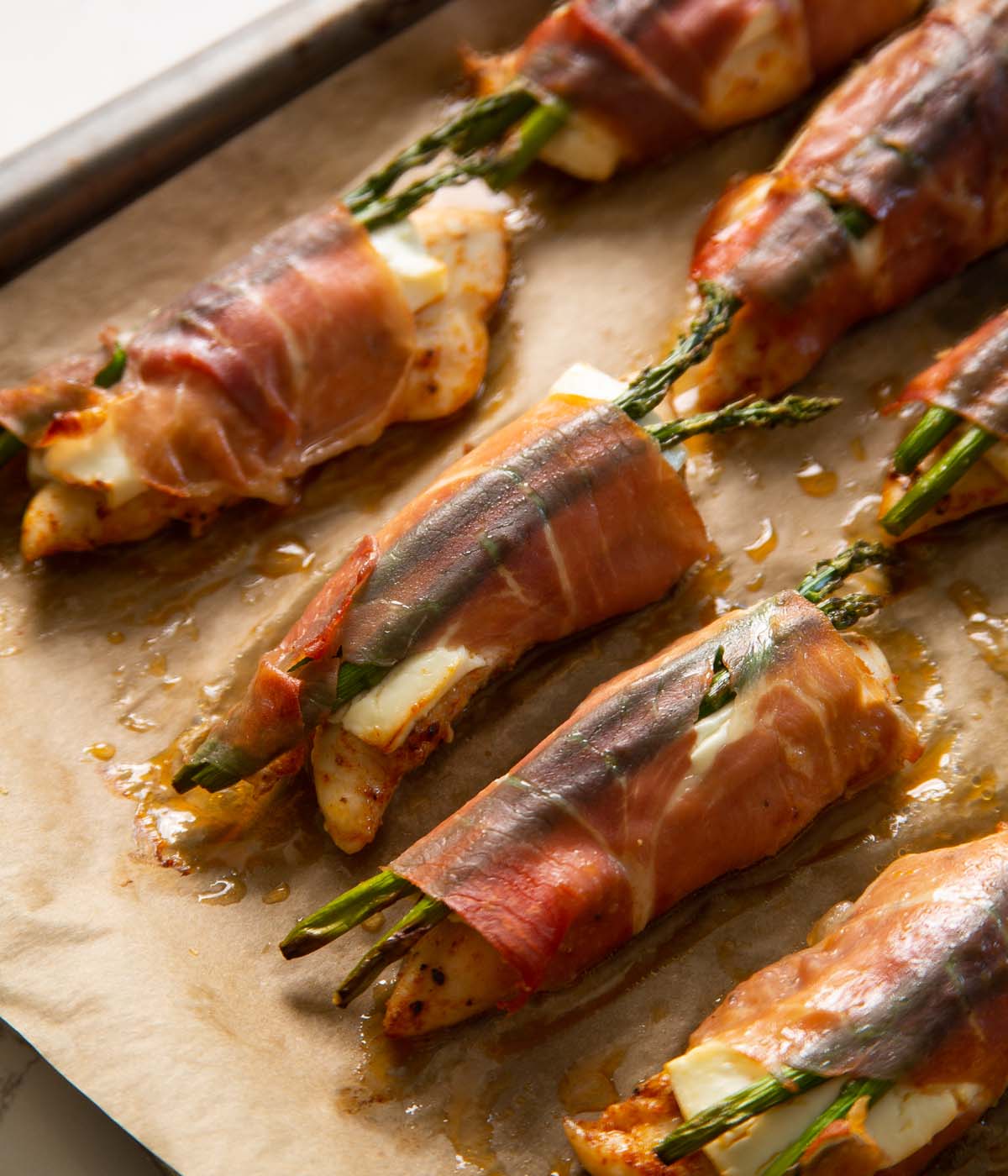 close up shot of chicken wrapped in prosciutto on baking tray fresh out the oven