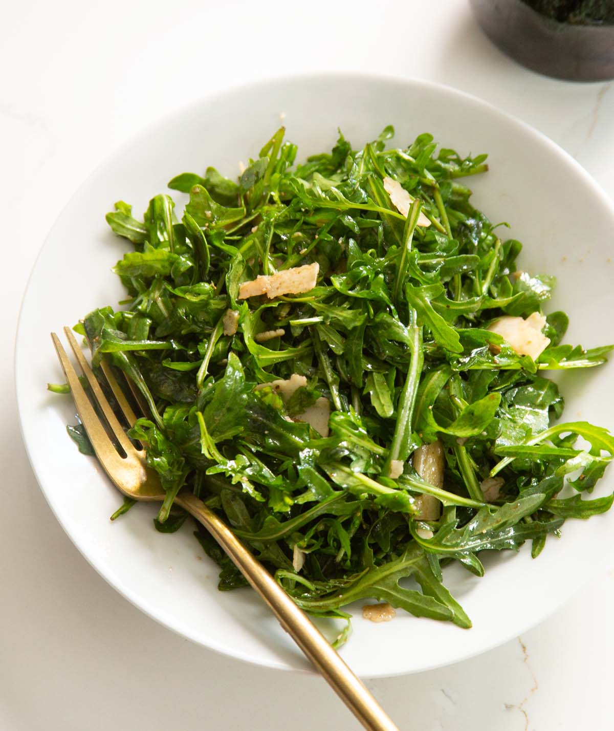 rocket salad in white bowl with gold fork