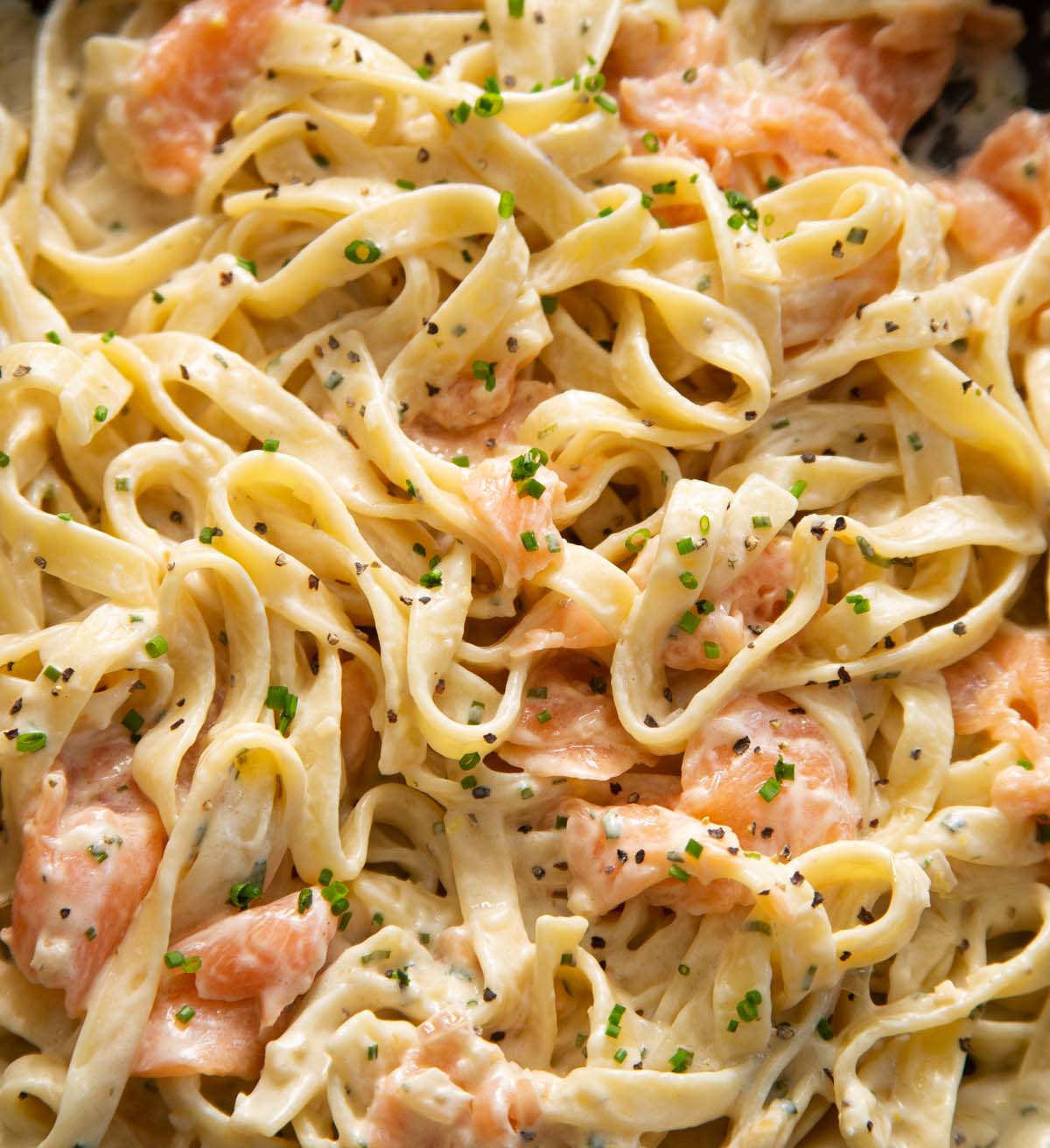 close up shot of pasta with smoked salmon in large pan