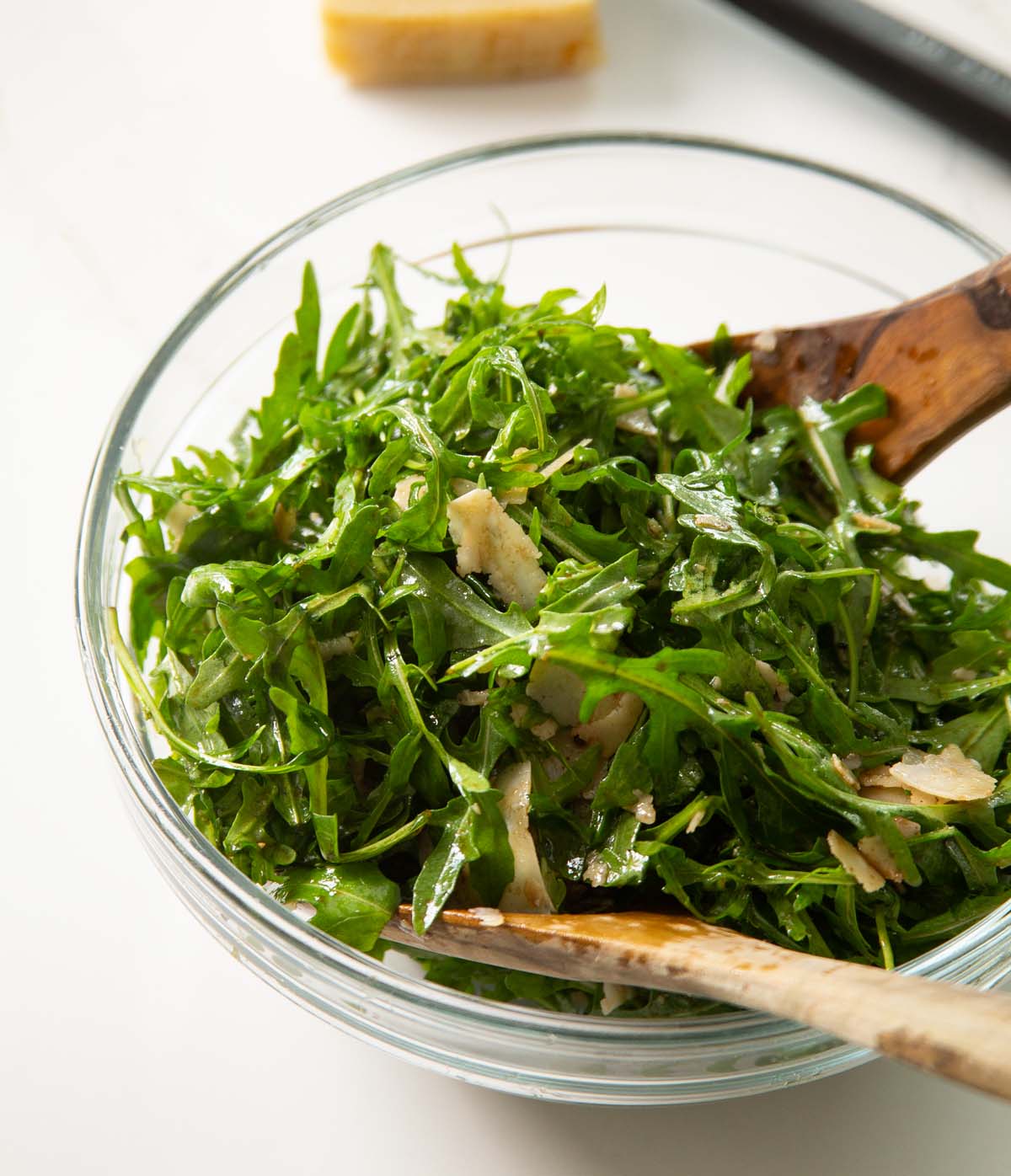rocket salad in large glass bowl with wooden salad tossers
