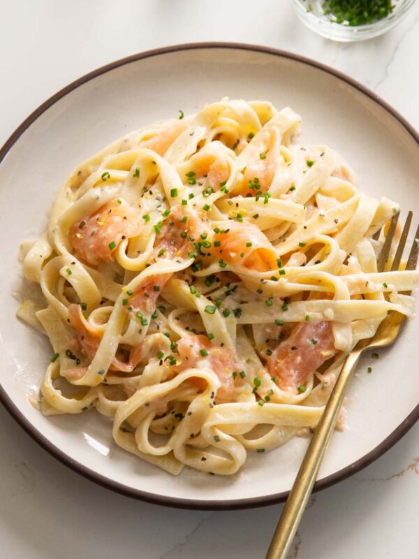 smoked salmon pasta served on small white plate with gold fork