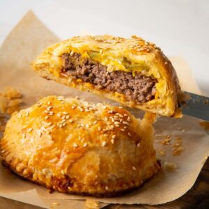close up shot of knife holding half of cheeseburger wellington showing filling