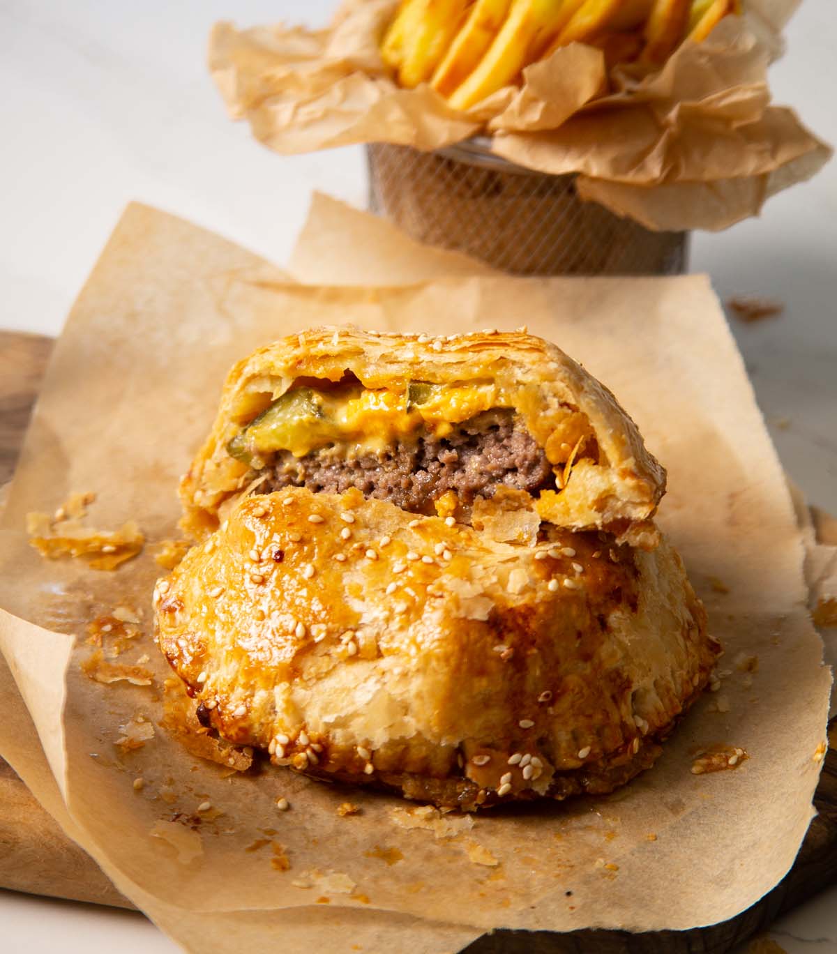 cheeseburger wellington on parchment paper with fries blurred in the background
